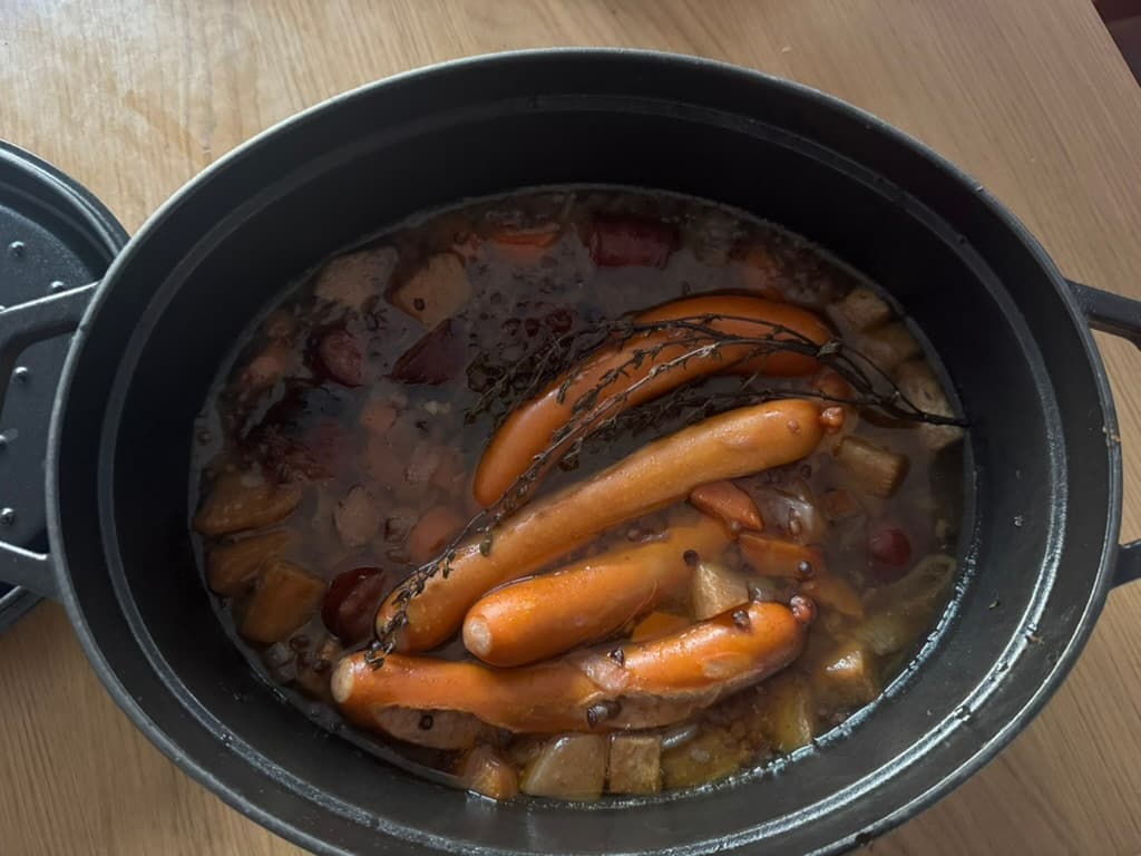 Plat de lentilles aux saucisses cuites en cocotte Staub, servies dans une assiette blanche